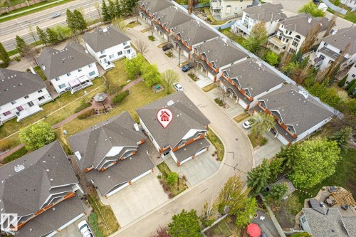 Townhome featuring a multi-gable roofline, attached garage, and paved driveway - 2550 Rabbit Hill Road Nw, Edmonton, AB 