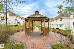 Central wooden gazebo with a shingled roof, set on a circular brick-paver patio - 