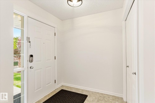 White paneled entry door with sidelite, light-colored tile flooring, and a flush-mount ceiling light fixture - 2550 Rabbit Hill Road Nw, Edmonton, AB 
