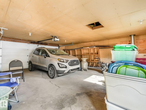 Attached garage with concrete flooring, overhead lighting, and an automatic garage door opener - 7520 130 Avenue Nw, Edmonton, AB 