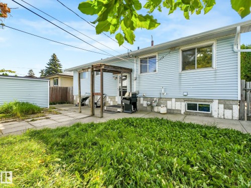 Rear exterior with light blue siding, an uncovered patio area, and a storage shed - 7520 130 Avenue Nw, Edmonton, AB 