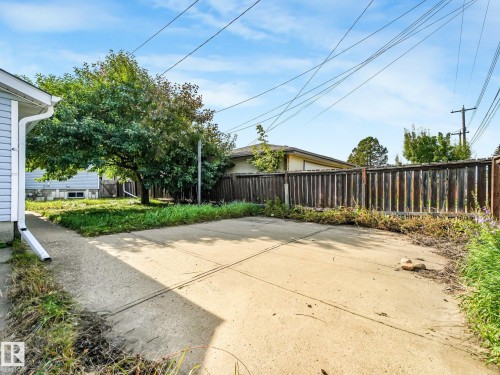 Concrete patio area with a wood fence perimeter and mature tree - 7520 130 Avenue Nw, Edmonton, AB 