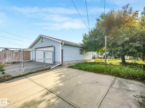 Detached garage with light blue siding, white trim, and a chain link fence with gated access - 7520 130 Avenue Nw, Edmonton, AB 