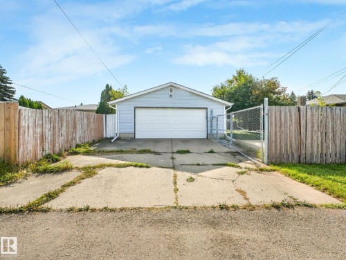 Detached garage with horizontal siding, a white garage door, and a concrete driveway - 7520 130 Avenue Nw, Edmonton, AB 