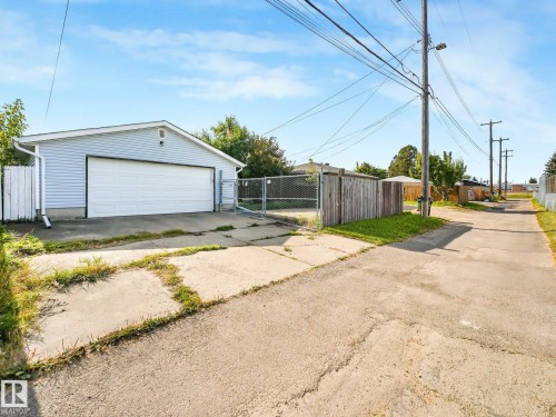Detached garage with horizontal siding, a white sectional garage door, and a downspout system - 7520 130 Avenue Nw, Edmonton, AB 