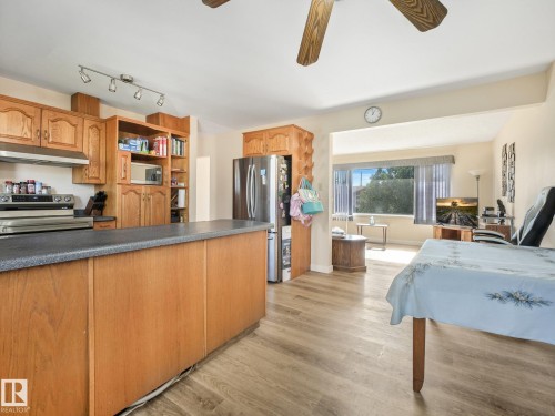 Kitchen featuring wood-finish cabinetry, stainless steel appliances, and a peninsula with a dark countertop - 7520 130 Avenue Nw, Edmonton, AB 