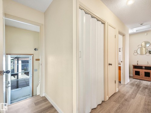 Hallway featuring wood-finish flooring, accordion folding door, and flush-mounted ceiling lighting - 7520 130 Avenue Nw, Edmonton, AB 