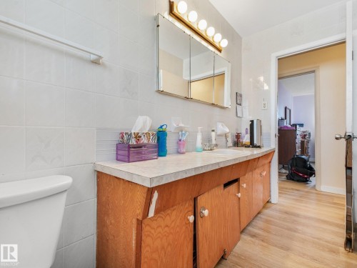 Vanity with wood-finish cabinetry, integrated sink, and laminate countertop - 7520 130 Avenue Nw, Edmonton, AB 