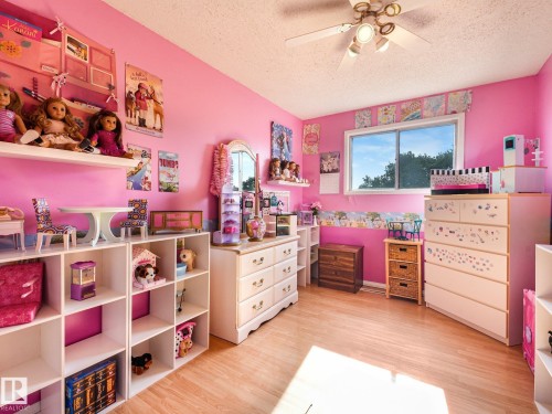 Wood-finish flooring, ceiling fan with integrated lighting, window with exterior views, built-in shelving, and white dresser - 7520 130 Avenue Nw, Edmonton, AB 