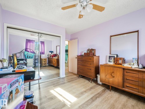 Wood-finish flooring, mirrored closet doors, ceiling fan with light fixture, and a solid core door - 7520 130 Avenue Nw, Edmonton, AB 