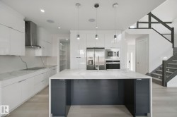 Gourmet kitchen with white cabinetry, stainless steel appliances, a large center island, and a walk-in pantry - 