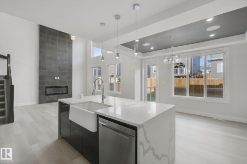 Kitchen island with a waterfall edge countertop, integrated farmhouse sink, and pendant lighting - 3699 Hummingbird Way Nw, Edmonton, AB 