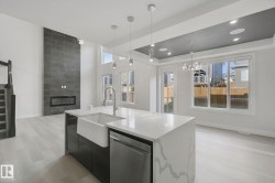 Kitchen island with a waterfall edge countertop, integrated farmhouse sink, and pendant lighting - 