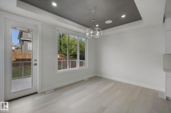 Recessed ceiling lighting, tray ceiling design, contemporary chandelier, large windows, and wood-finish flooring - 