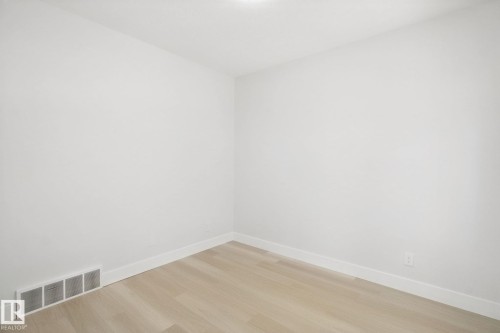 Light wood-finish flooring with white baseboards, bright white walls, and an overhead flush-mount light fixture - 3699 Hummingbird Way Nw, Edmonton, AB 