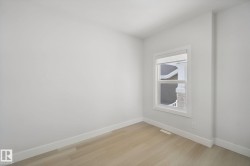 Light wood-finish flooring, white walls, and a window with white trim - 