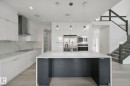 Gourmet kitchen with white cabinetry, stainless steel appliances, a large center island, and a walk-in pantry - 3699 Hummingbird Way Nw, Edmonton, AB 