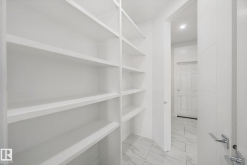 Built-in shelving with multiple storage levels, a solid panel door with chrome hardware, and tile flooring - 3699 Hummingbird Way Nw, Edmonton, AB 