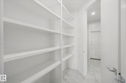 Built-in shelving with multiple storage levels, a solid panel door with chrome hardware, and tile flooring - 