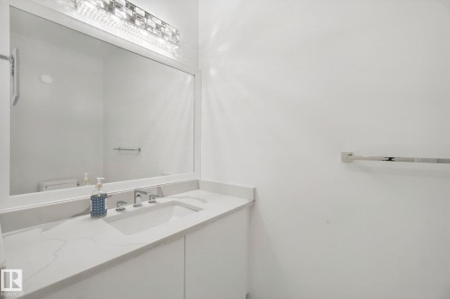 Integrated vanity with a rectangular undermount sink, a chrome two-handle faucet, and a large wall-mounted mirror - 3699 Hummingbird Way Nw, Edmonton, AB 