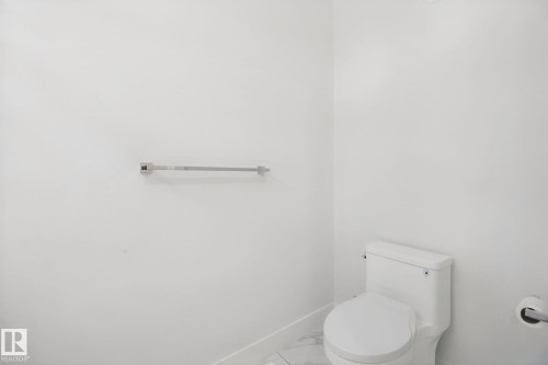 White ceramic toilet with a matching toilet paper holder and a chrome towel bar - 3699 Hummingbird Way Nw, Edmonton, AB 