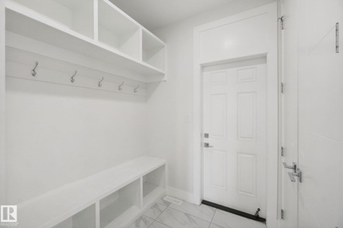 Entryway featuring built-in shelving, integrated bench seating, wall-mounted coat hooks, and durable tile flooring - 3699 Hummingbird Way Nw, Edmonton, AB 