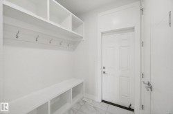 Entryway featuring built-in shelving, integrated bench seating, wall-mounted coat hooks, and durable tile flooring - 