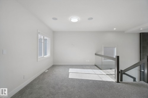 Carpeted landing featuring multiple windows, recessed lighting, and a contemporary glass and wood-finish railing - 3699 Hummingbird Way Nw, Edmonton, AB 