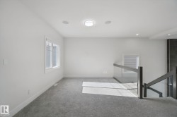 Carpeted landing featuring multiple windows, recessed lighting, and a contemporary glass and wood-finish railing - 