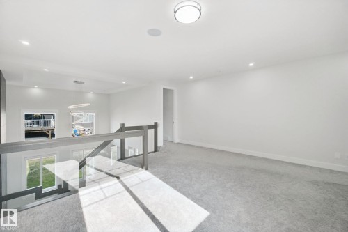 Recessed lighting, wall-to-wall carpeting, contemporary glass railing, modern semi-flush mount light fixture, and built-in ceiling speaker - 3699 Hummingbird Way Nw, Edmonton, AB 
