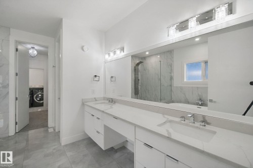 Dual vanity with integrated sinks and white countertops, full-width mirror, and tiled flooring - 3699 Hummingbird Way Nw, Edmonton, AB 
