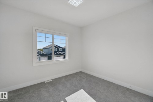 Neutral wall color, gray carpeting, ample natural light, contemporary light fixture, white window trim - 3699 Hummingbird Way Nw, Edmonton, AB 