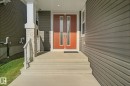 Entryway featuring a double door with vertical glass inserts, concrete steps with railing, stone-clad pillar, and horizontal siding - 3699 Hummingbird Way Nw, Edmonton, AB 