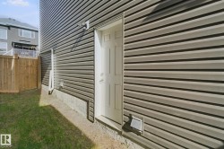 Brown horizontal siding, white exterior door, concrete foundation, wood fence, and a grass lawn - 