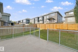 Concrete patio with glass panel railing and a private wood fence - 