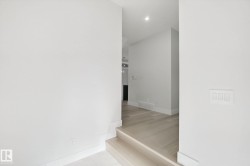 Recessed lighting illuminates the wood-finish flooring and white walls - 