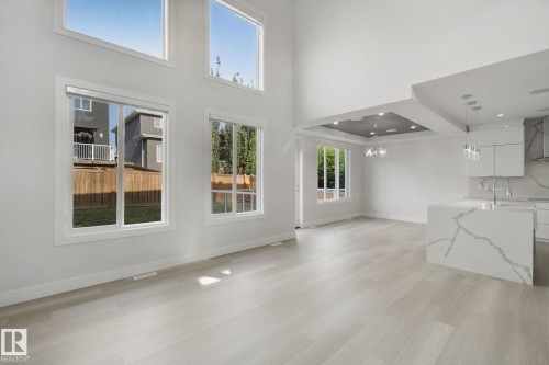 Vaulted ceilings with large windows, light wood-finish flooring, recessed lighting, kitchen island with waterfall counter, and pendant lighting - 3699 Hummingbird Way Nw, Edmonton, AB 