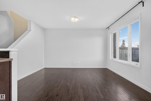 Wood-finish flooring throughout, bright white walls, large multi-pane window, and a built-in staircase - 2145 28 Street Nw, Edmonton, AB 