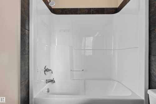 White bathtub and shower combination unit featuring a chrome shower head and faucet - 2145 28 Street Nw, Edmonton, AB 