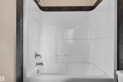White bathtub and shower combination unit featuring a chrome shower head and faucet - 