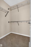Walk-in closet with wire shelving, integrated hanging rods, and carpet flooring - 