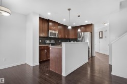 Wood-finish flooring throughout, kitchen with dark wood cabinetry, stainless steel appliances, pendant lighting, and recessed lighting - 