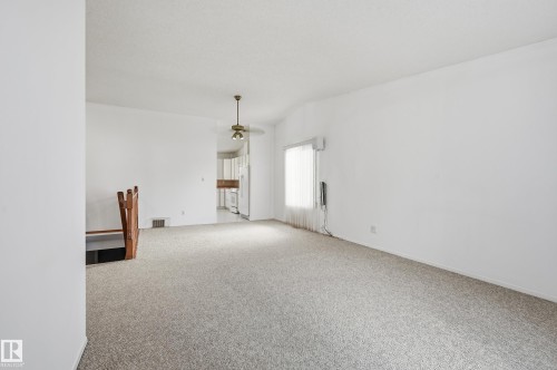 Neutral-toned carpet flooring, vaulted ceiling, metal-finish ceiling fan, and wooden staircase railing - #19 10 Grange Dr, St. Albert, AB 