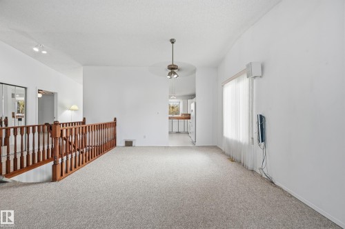 Vaulted ceilings, carpeted flooring, and a wood-railing banister featuring turned spindles, illuminated by a central ceiling fan with integrated lighting - #19 10 Grange Dr, St. Albert, AB 