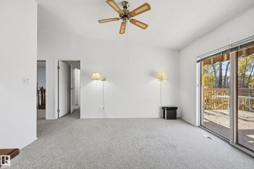 Sliding glass doors, neutral carpeting, vaulted ceiling with a five-blade ceiling fan, and dual wall-mounted light fixtures - #19 10 Grange Dr, St. Albert, AB 