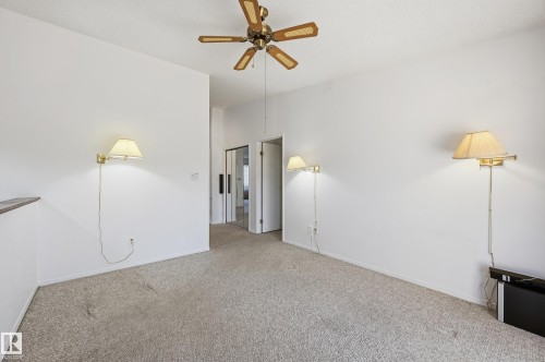 Room featuring neutral carpeting, a central ceiling fan with integrated lighting, and three wall-mounted sconce fixtures - #19 10 Grange Dr, St. Albert, AB 