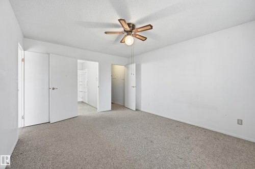 Room featuring neutral wall-to-wall carpeting, a ceiling fan with integrated lighting, and multiple interior hinged doors - #19 10 Grange Dr, St. Albert, AB 