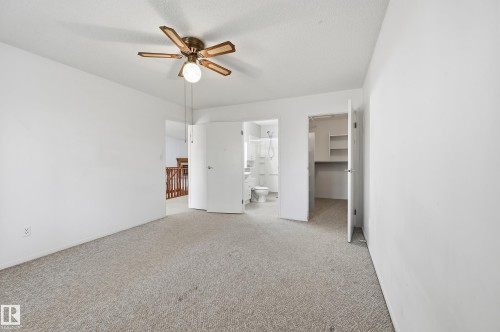 Neutral-toned wall-to-wall carpeting, ceiling fan with integrated lighting, reach-in closet with built-in shelving, and white interior doors - #19 10 Grange Dr, St. Albert, AB 
