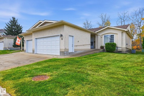 Stucco exterior featuring a double-bay garage, concrete driveway, and an exterior ramp leading to the entryway - #19 10 Grange Dr, St. Albert, AB 