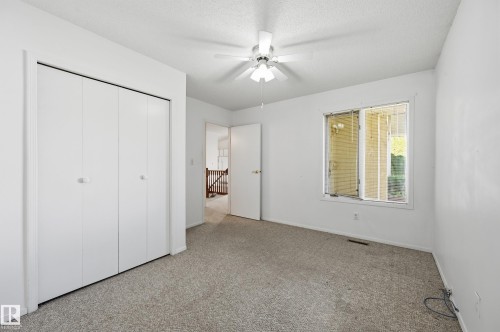 Neutral-toned carpeted flooring, white bi-fold closet doors, central ceiling fan with integrated light fixture, and window with exterior exposure - #19 10 Grange Dr, St. Albert, AB 